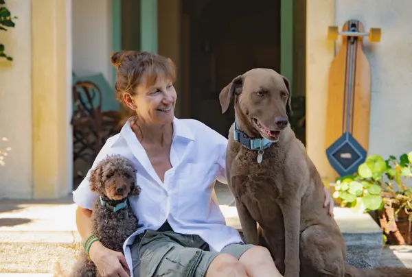 Petra Dürr sitzt mit ihren Hunden Victor und Emilio auf einer Treppe