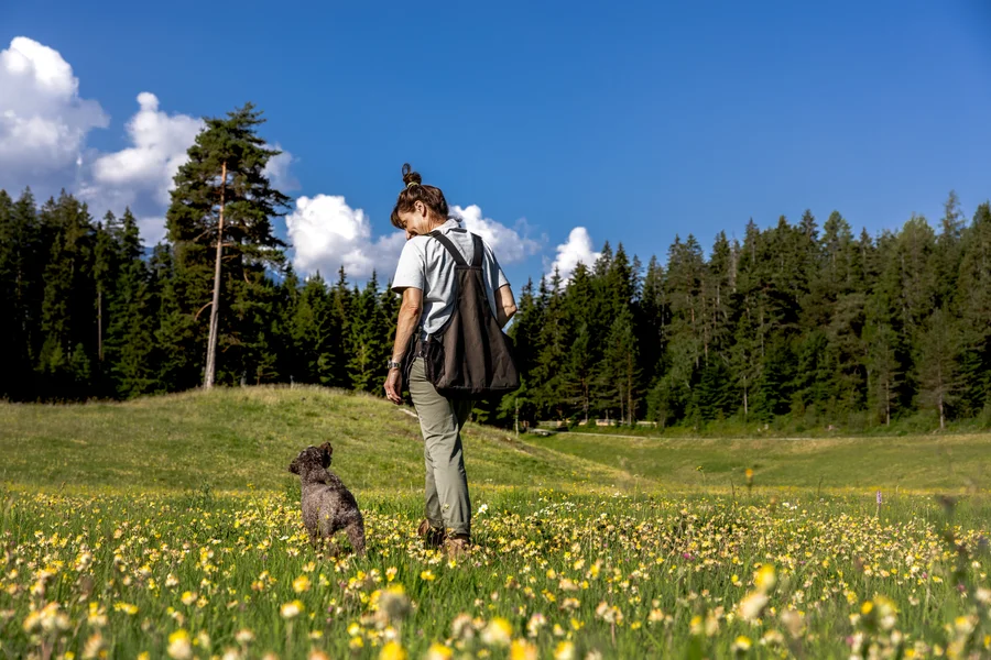 Petra geht mit einem kleinen Hund über eine Blumenwiese