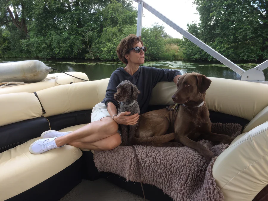 Petra sitzt mit ihren beiden Hunden auf einem Boot